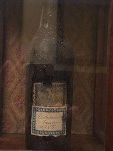 Dark glass bottle of artisanal balsamic vinegar with vintage label, displayed in rustic wooden case