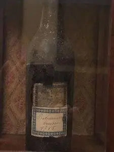 Vintage balsamic vinegar bottle with ornate label, displayed in rustic wooden case