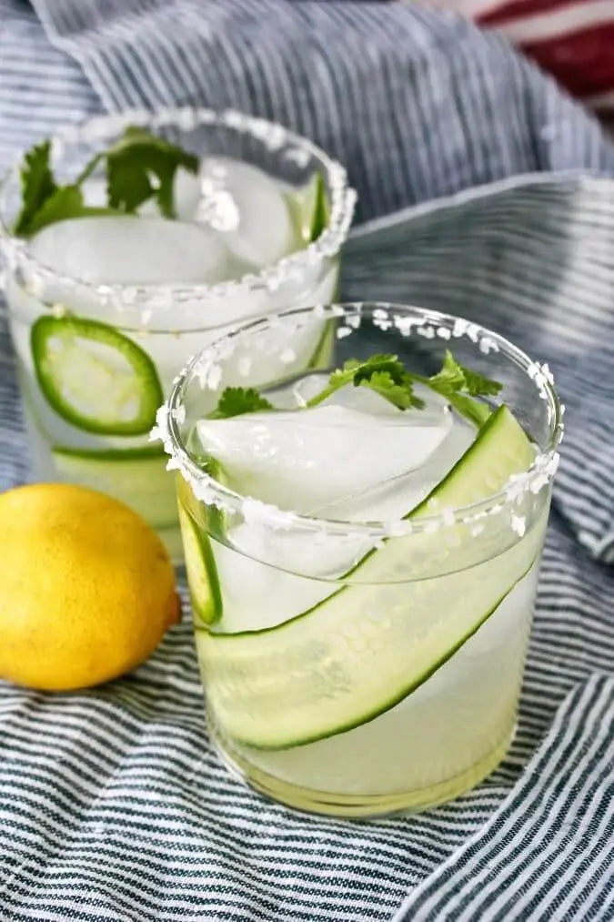 Cucumber lemonade with ice, cilantro, and salted rim on striped cloth