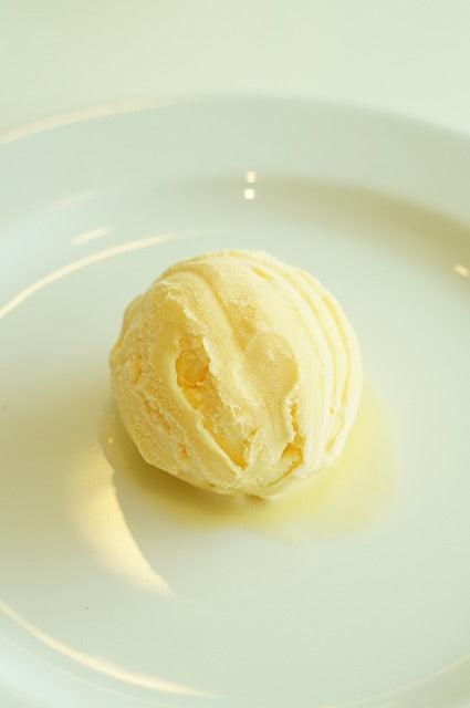 Creamy vanilla ice cream scoop on white plate, drizzled with golden olive oil for gourmet dessert
