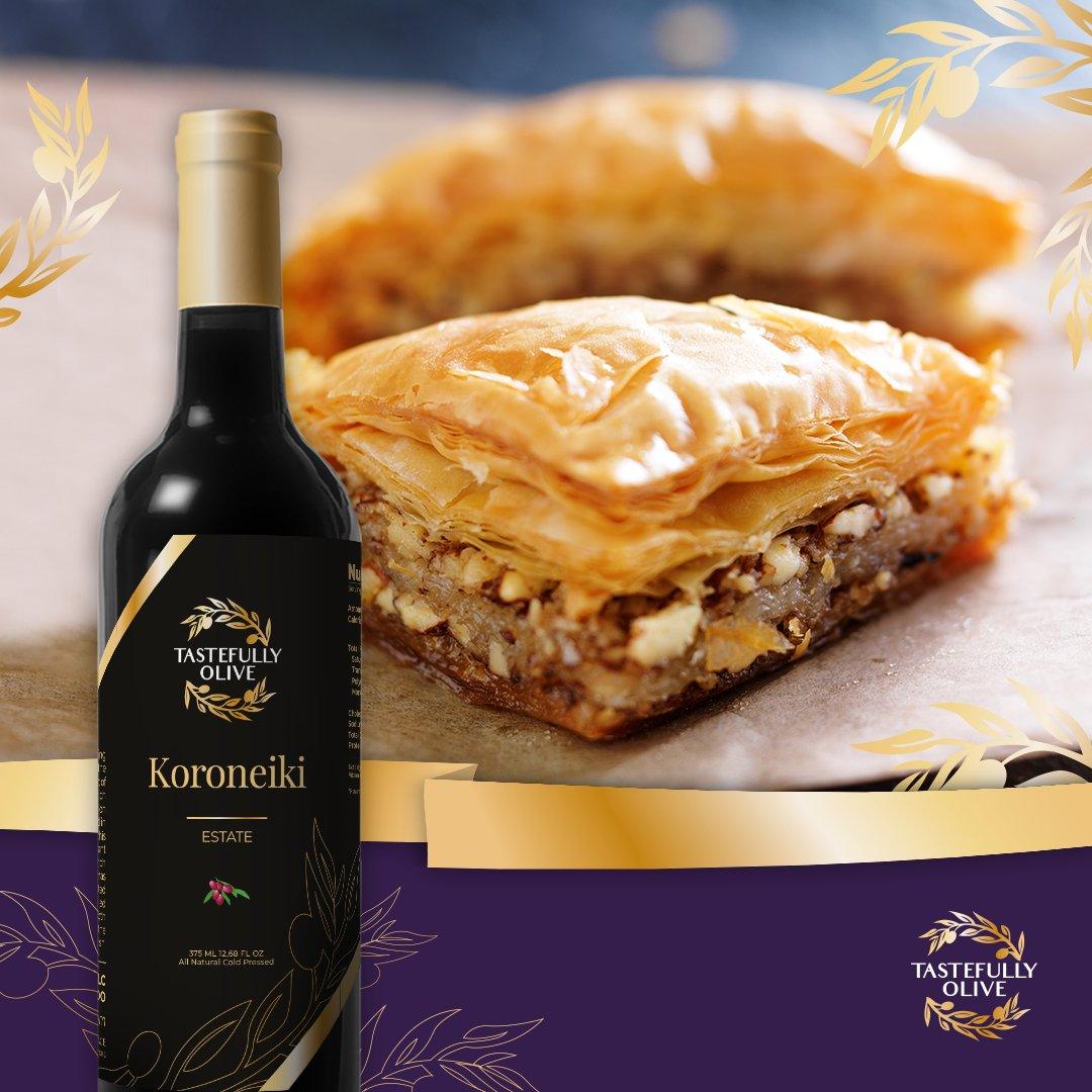 Koroneiki Estate olive oil bottle beside golden baklava, featuring flaky layers and nuts, perfect for gourmet cooking.
