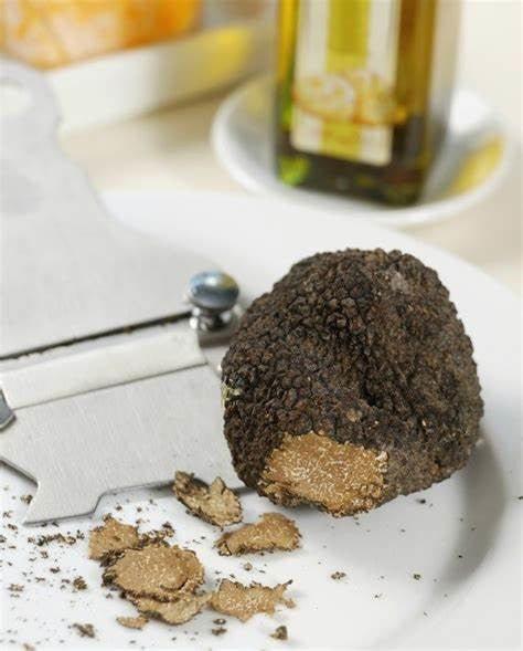 Fresh black truffle with shavings on plate, olive oil bottle in background