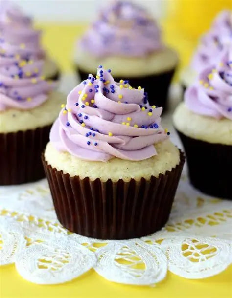 Purple frosted cupcakes with yellow and blue sprinkles on lace doily