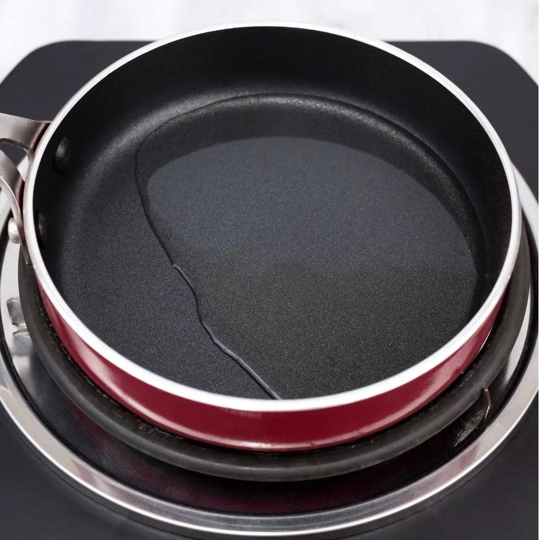 Olive oil in a red non-stick pan on stovetop, ready for cooking