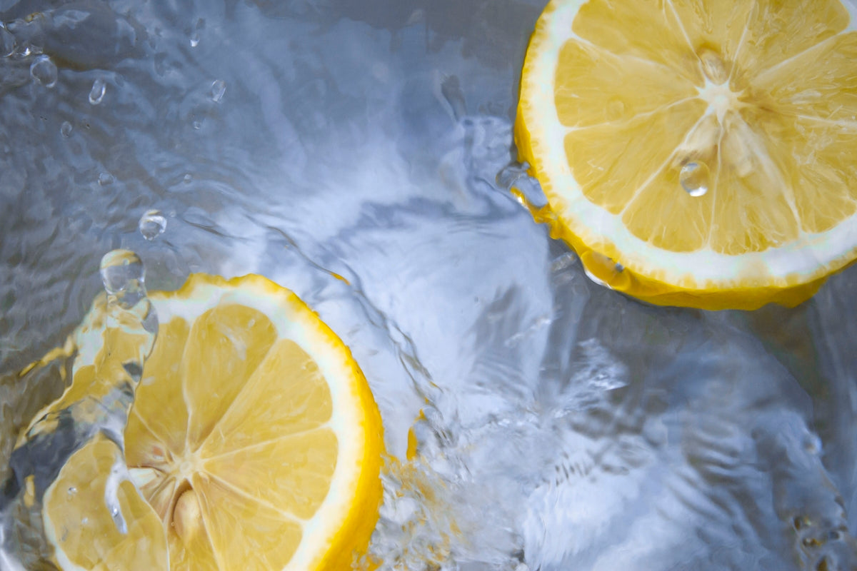 Fresh lemon slices splashing in water, vibrant citrus for cooking and dressings