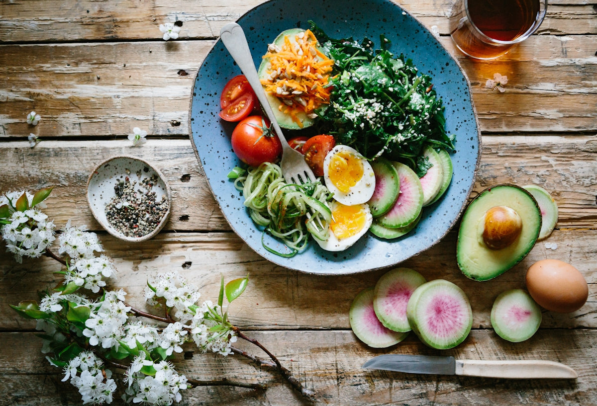 Fresh salad with avocado, radish, eggs, and greens on rustic wood, perfect with premium olive oil