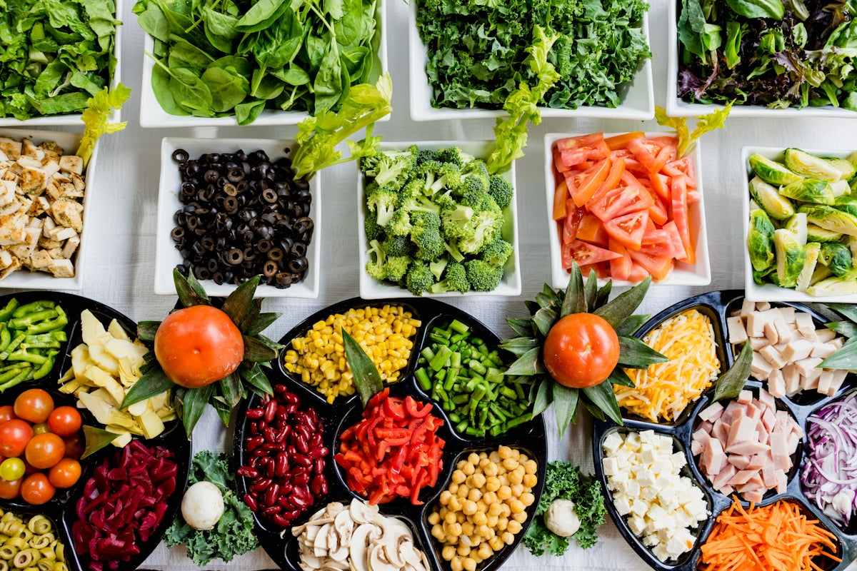 Fresh salad bar with greens, veggies, olives, cheese, and proteins for healthy meals
