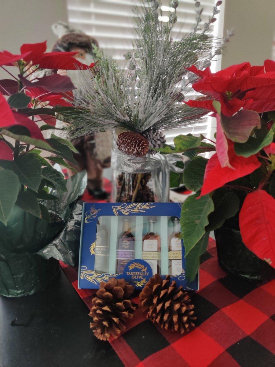 Holiday gift set with artisanal olive oils and vinegars, surrounded by poinsettias and pinecones on plaid tablecloth
