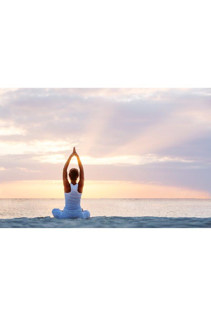 Woman practicing yoga on beach at sunset, peaceful ocean view