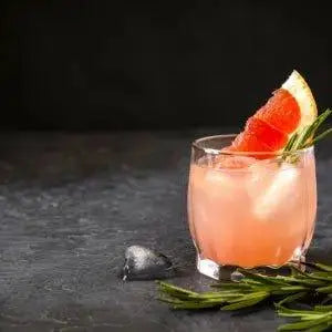 Pink cocktail with grapefruit slice and rosemary garnish on dark surface