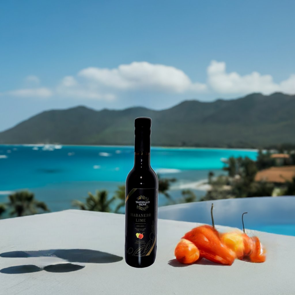 A black bottle labeled "Lime Habanero Infused Olive Oil" from Tastefully Olive is placed on a surface next to two orange peppers, with a scenic view of a tropical beach and mountains in the background. This showcases our exclusive Lime Habanero Infused Olive Oil.